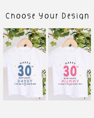 two white t-shirts with birthday messages for a father and a mother, celebrating their 30th birthdays. The t-shirts are hanging on a wooden hanger, with a plant in the background.