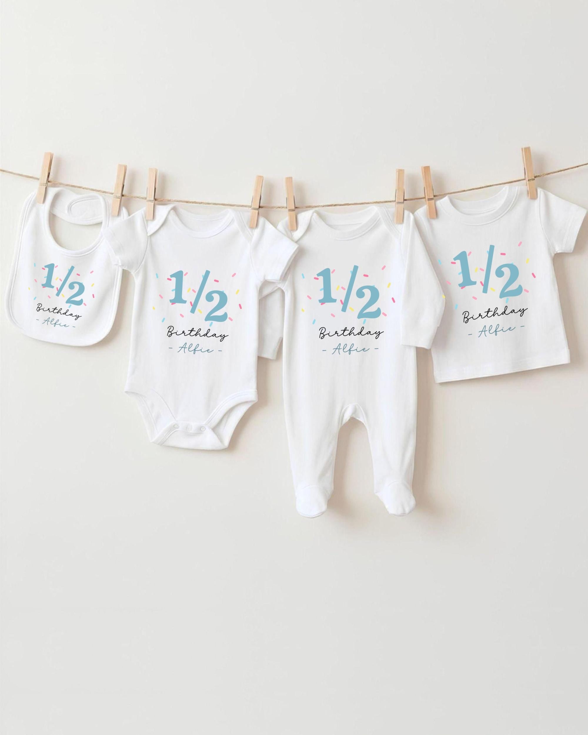 A collection of baby clothes, including onesies and bibs, hanging on a clothesline.