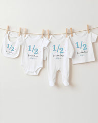 A collection of baby clothes, including onesies and bibs, hanging on a clothesline.