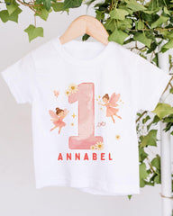 A white t-shirt with a pink number one and two-tailed fairy design, along with the text "Annabel" printed on it.