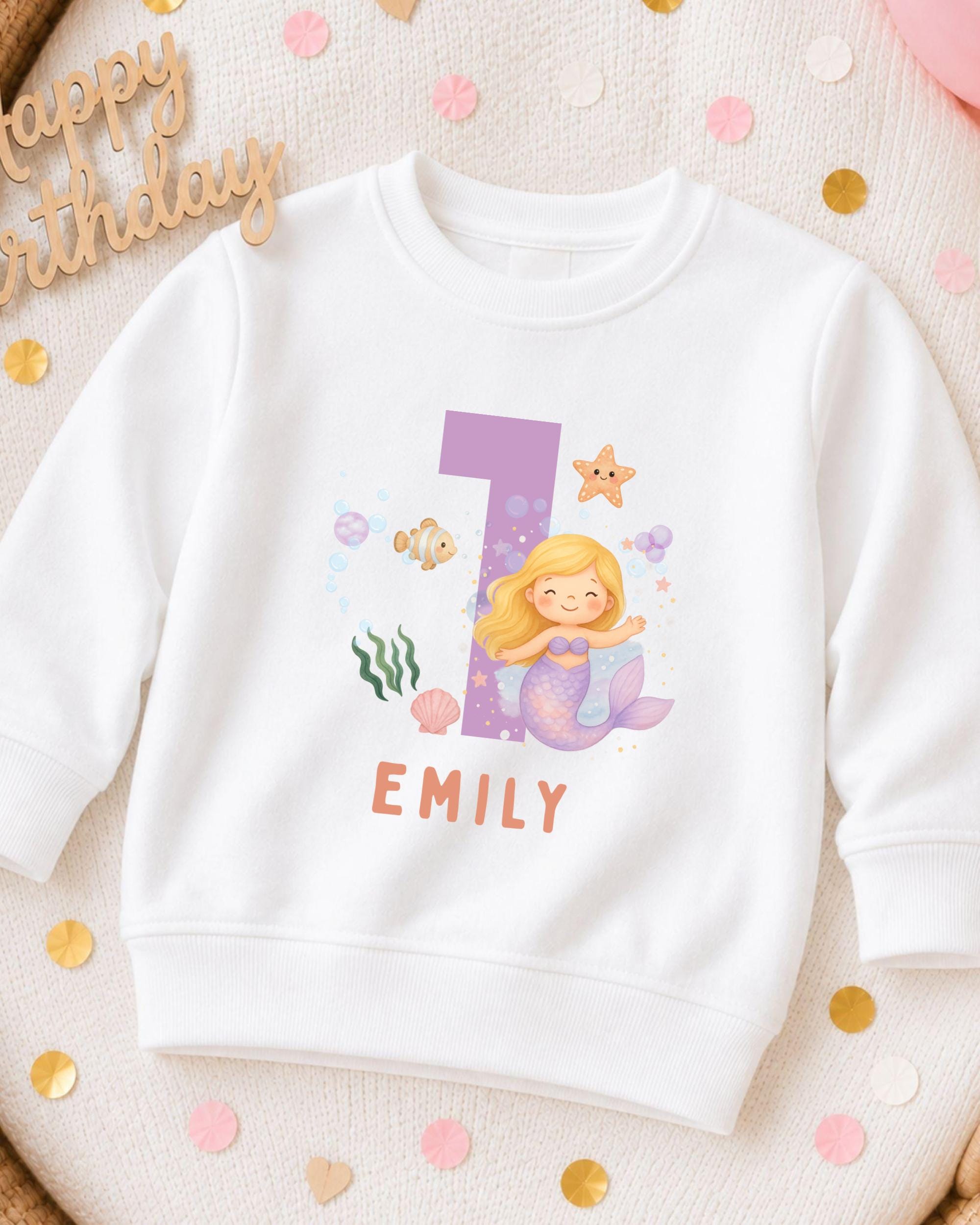 A white sweatshirt with a mermaid character and the number 1 printed on it, along with the name "EMILY" below the number.