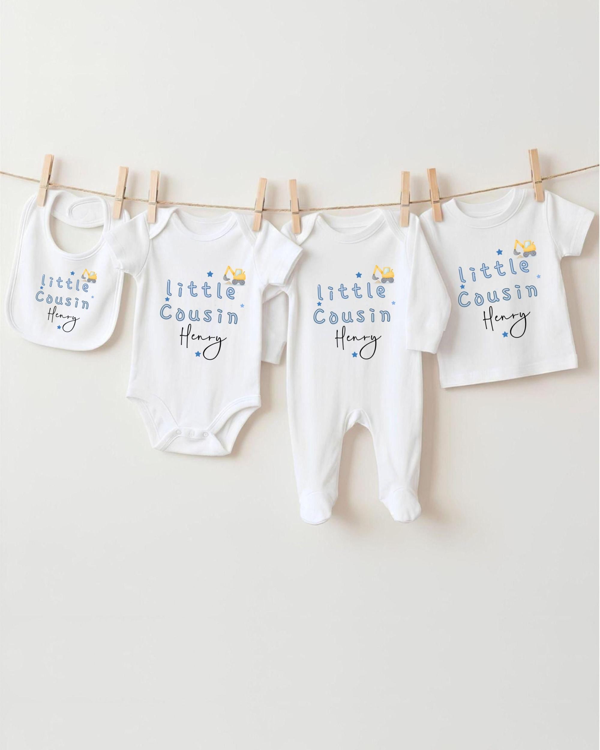 A row of four white baby clothes, including onesies and pajamas, hanging on a clothesline.