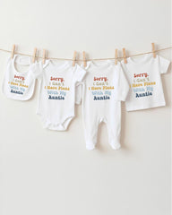 a row of baby clothes hanging on a clothesline, with each piece featuring a different message printed on it.