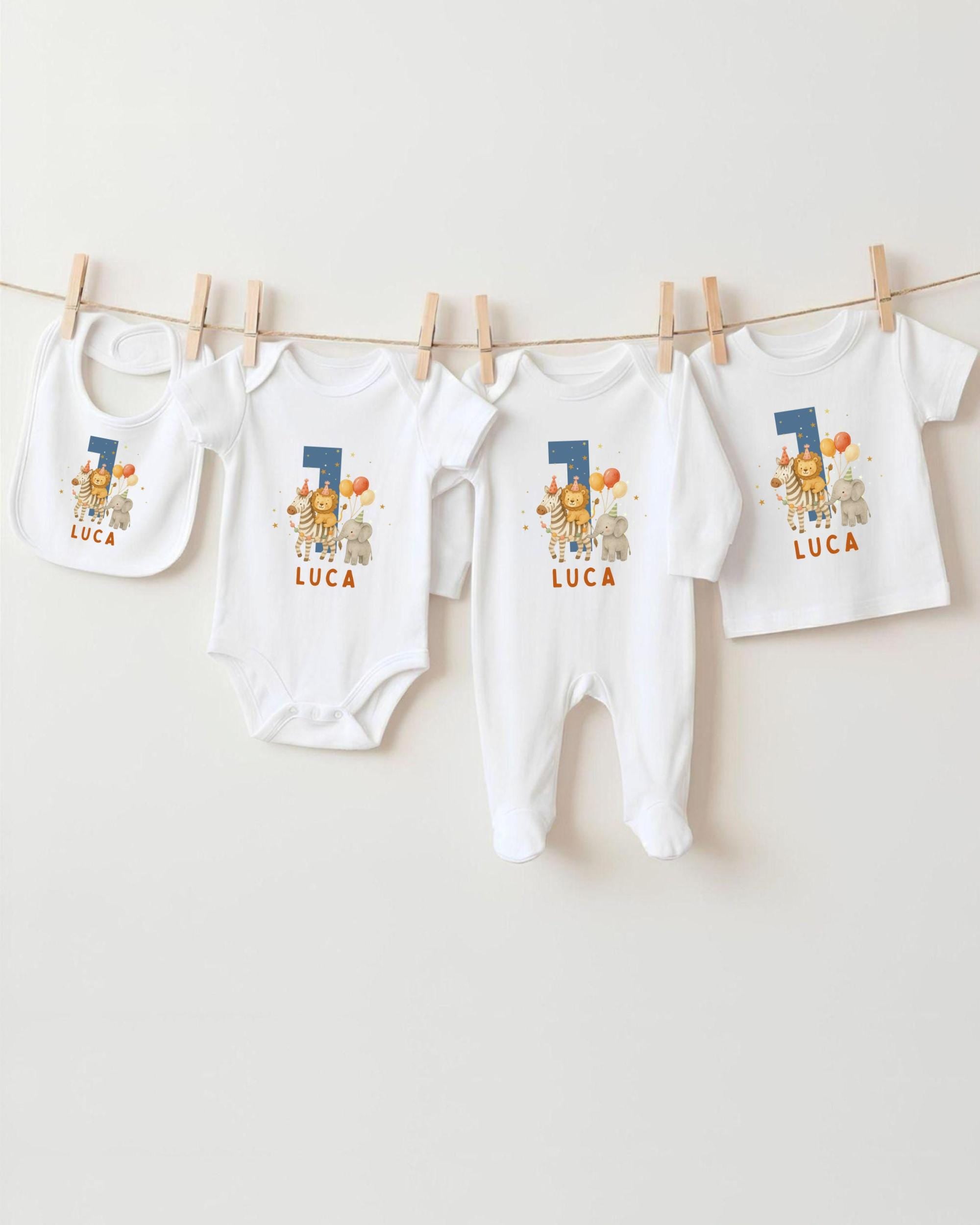 A collection of white baby clothes, including onesies and bibs, with the name "LUCA" printed on them.