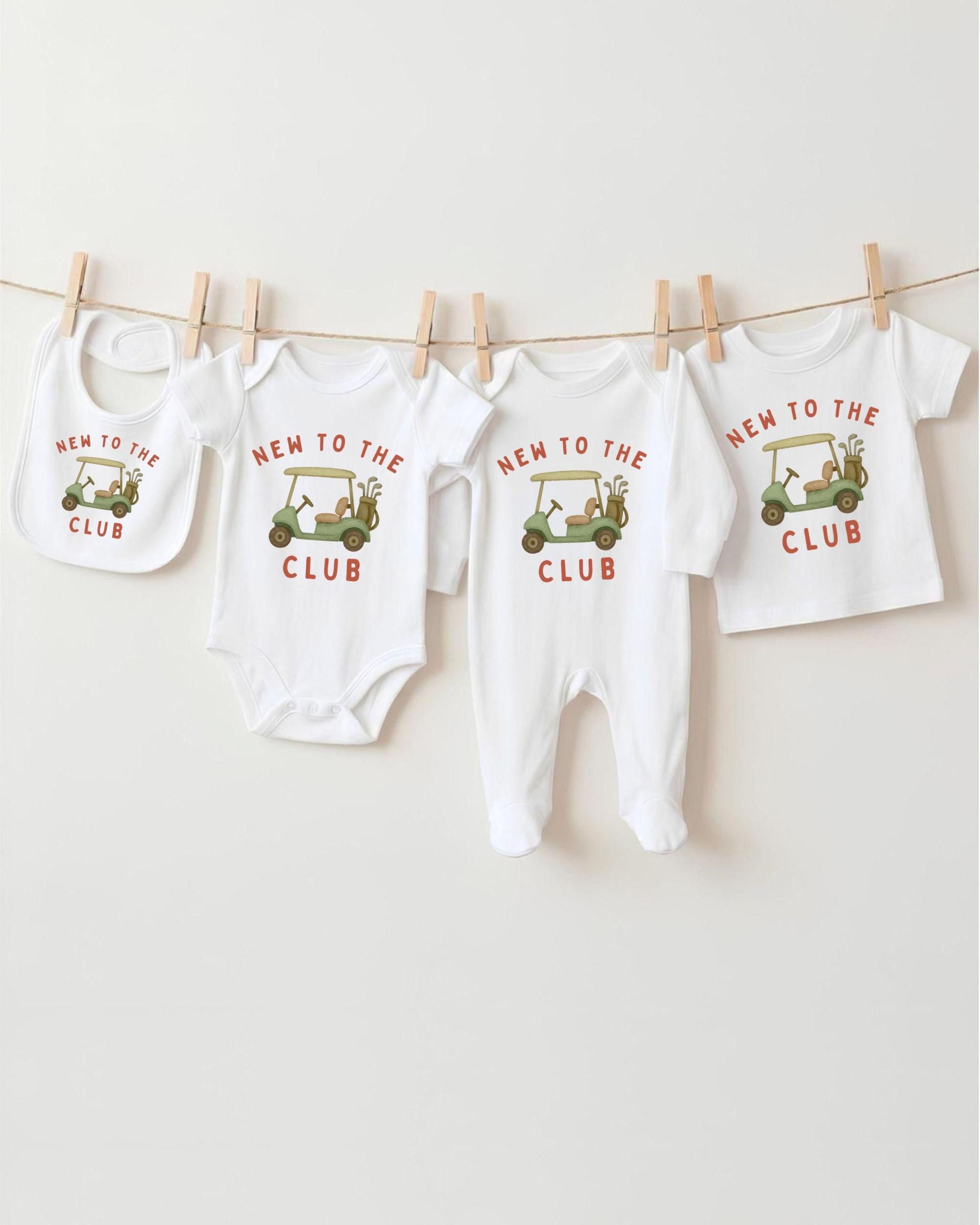 A row of four white baby clothes with the text "NEW TO THE CLUB" printed on them, along with a golf cart graphic.