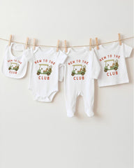 A row of four white baby clothes with the text "NEW TO THE CLUB" printed on them, along with a golf cart graphic.