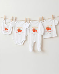A row of white baby clothes with the name " Jessica " printed on them, along with an illustration of a strawberry.