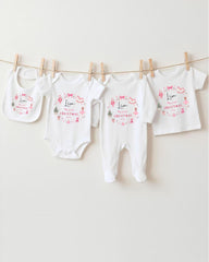 A row of four white baby clothes, including onesies and bibs, hanging on a clothesline.