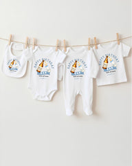 A collection of four white baby clothes, including onesies and bibs, hanging on a clothesline.