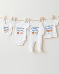 A collection of baby clothes, including onesies and pajamas, hanging on a clothesline.