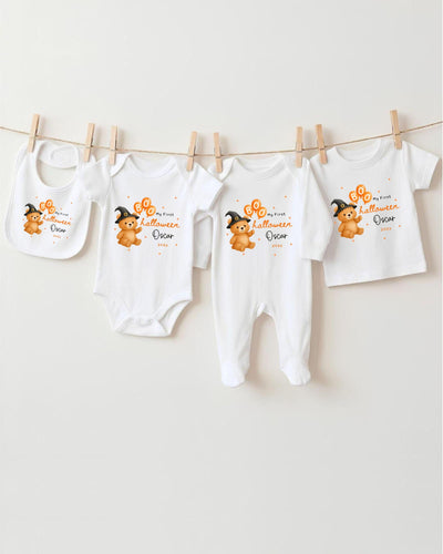 A collection of baby clothes, including bodysuits and bibs, hanging on a clothesline.