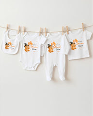 A collection of baby clothes, including onesies and bibs, hanging on a clothesline.