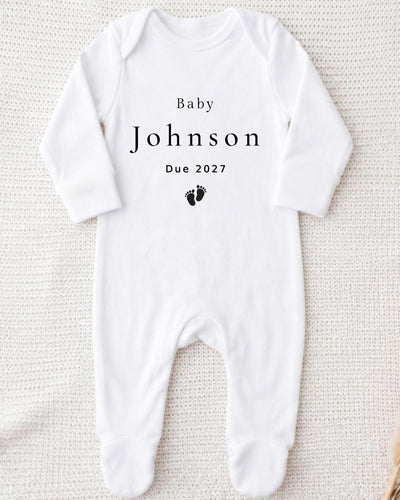 A white bodysuit with the text "Baby Johnson Due 2027" printed on it.