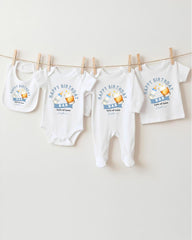 A collection of white baby clothes, including onesies and bibs, hanging on a clothesline.