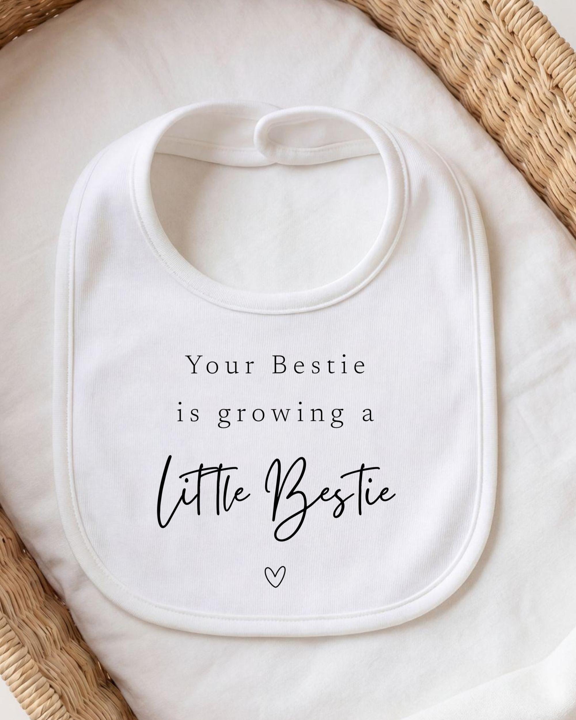 A white bib with a message printed on it, placed on a white cloth.