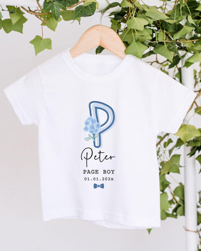A white t-shirt with a blue floral design and text printed on it, hanging on a wooden hanger.
