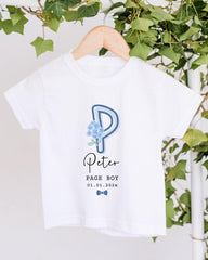 A white t-shirt with a blue floral design and text printed on it, hanging on a wooden hanger.