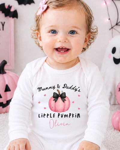 A smiling baby girl wearing a white bodysuit with a pumpkin design and text that says "Mummy & Daddy's Little Pumpkin Olivia".