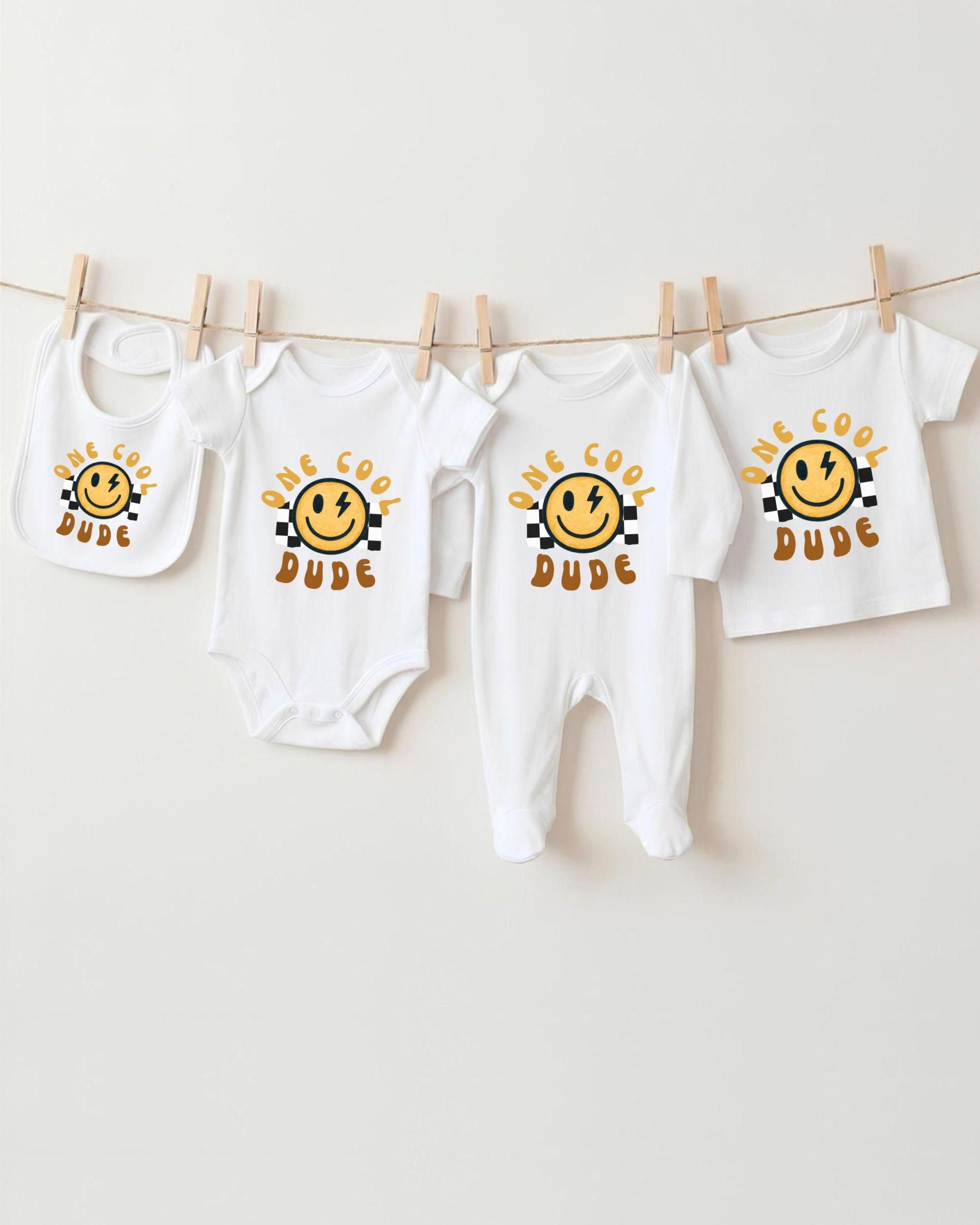 A collection of baby clothes, including onesies and bibs, hanging on a clothesline.