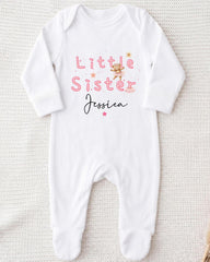 A white onesie with the text "Little Sister Jessica" printed on it.