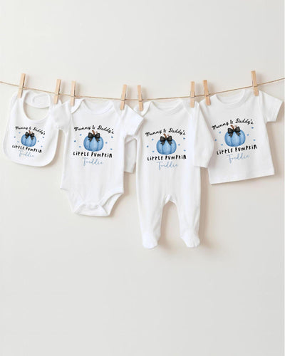 A row of four white baby clothes with the text "Mum & Dad's LITTLE PUMPKIN FADDLE" printed on them, hanging on a clothesline.