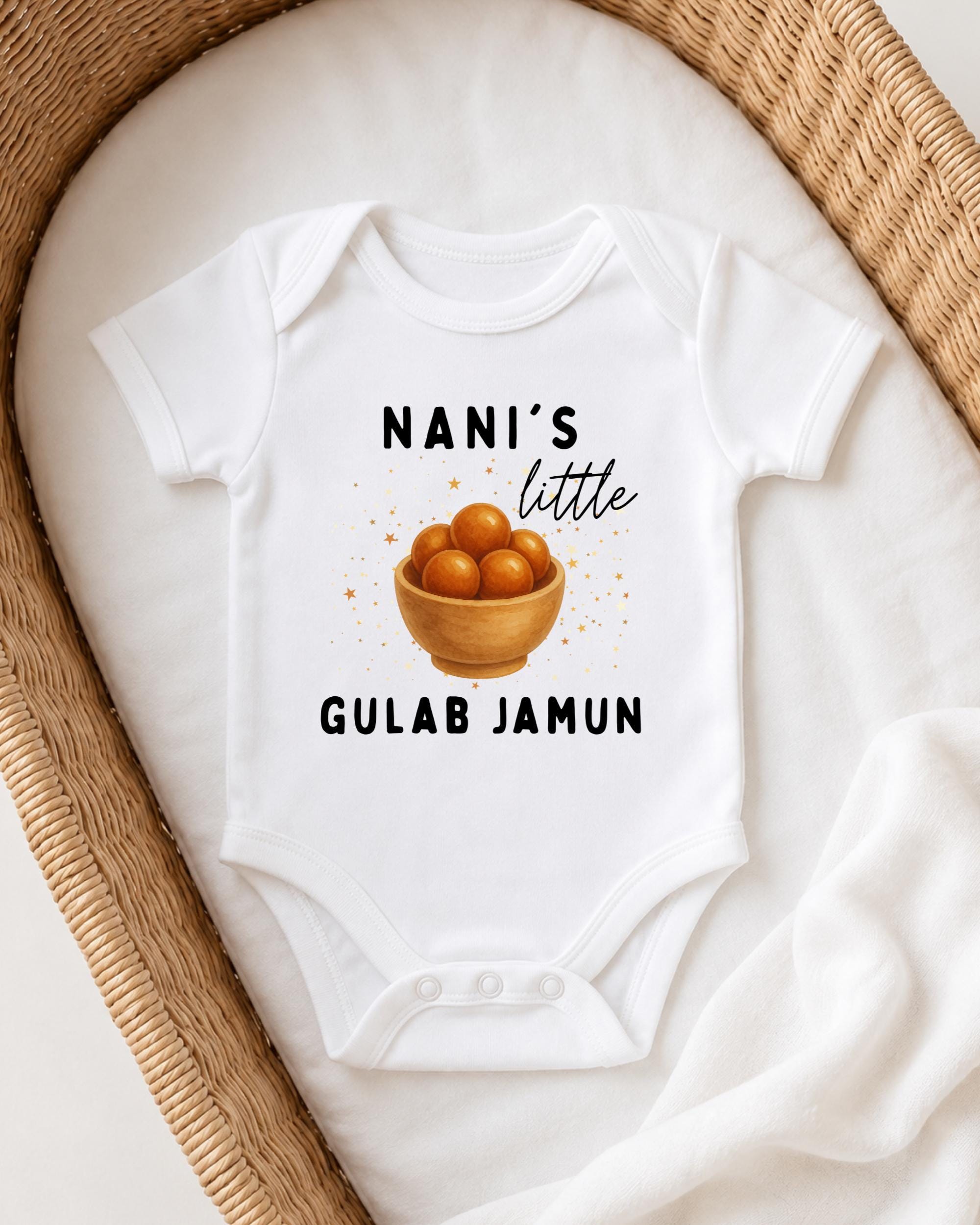 A white baby onesie with a graphic of a bowl of fruit and text printed on it, placed on a white blanket.