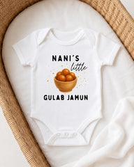 A white baby onesie with a graphic of a bowl of fruit and text printed on it, placed on a white blanket.