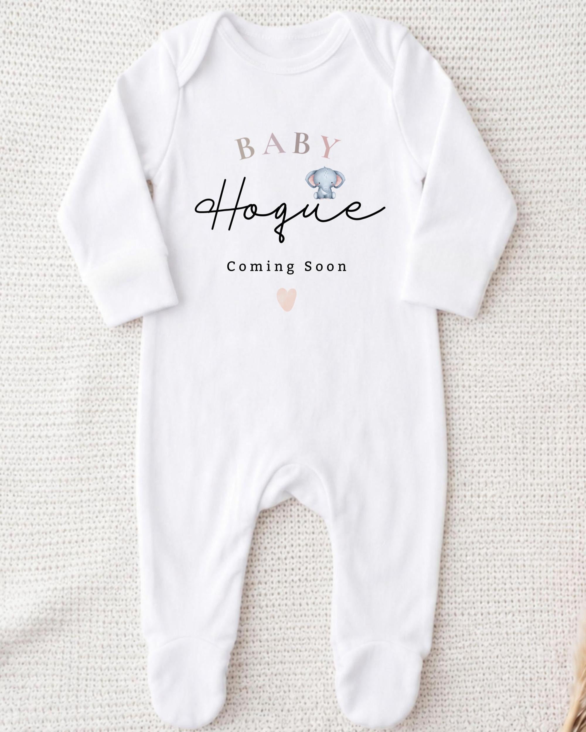 A white onesie with the text "BABY Hogue" printed on it, along with a small heart symbol.