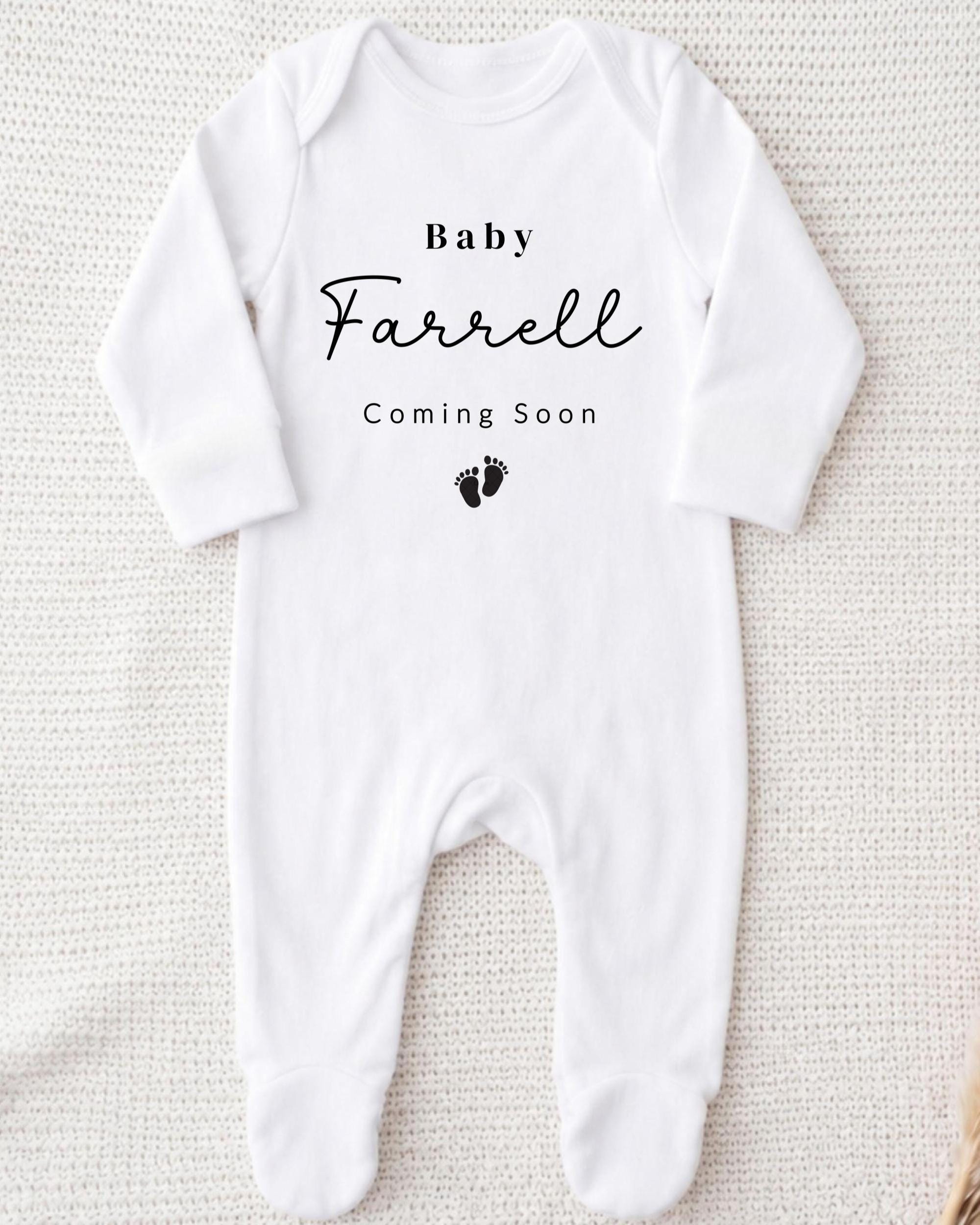 A white onesie with the text "Baby Farrell Coming Soon" printed on it.