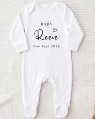 A white onesie with the text "BABY Reeve Due Sept 2028" printed on it.
