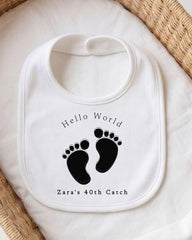 A white bib with a personalized message and a graphic of baby feet.