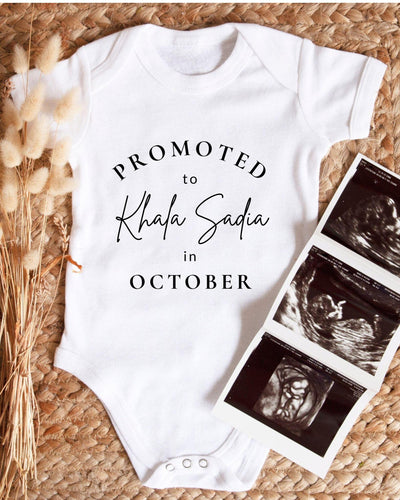 A white baby bodysuit with text that reads "PROMOTED to Khala Sadia in October" is displayed alongside a set of three black and white baby ultrasound images.