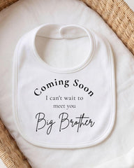 A white bib with text that says "Coming Soon I can't wait to meet you Big Brother".