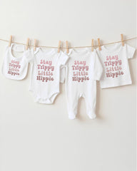 A collection of baby clothes, including onesies and bibs, hanging on a clothesline.