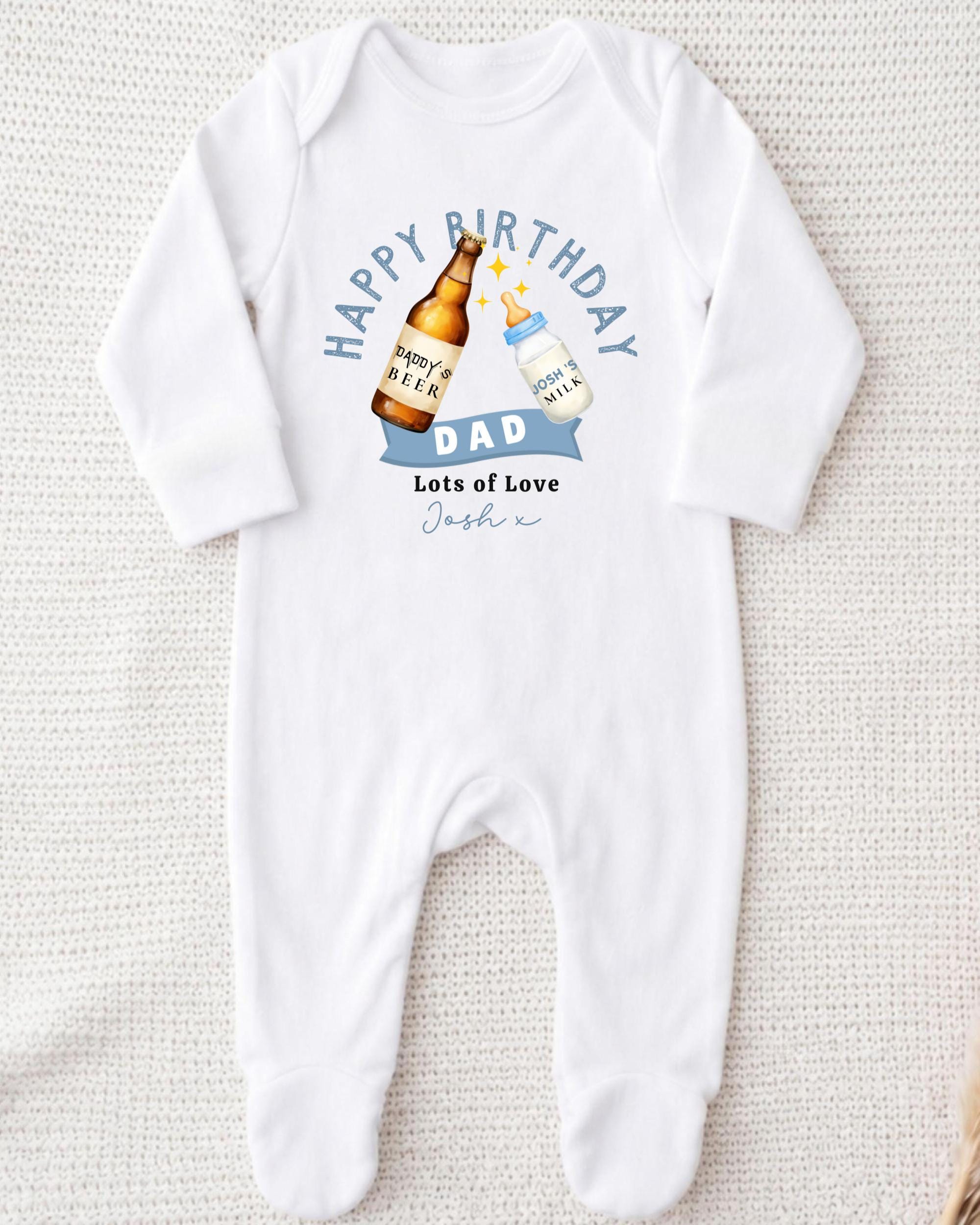 A white onesie with a graphic design on it, featuring a bottle of beer and a baby bottle, along with the text "Happy Birthday Dad Lots of Love Joshi".