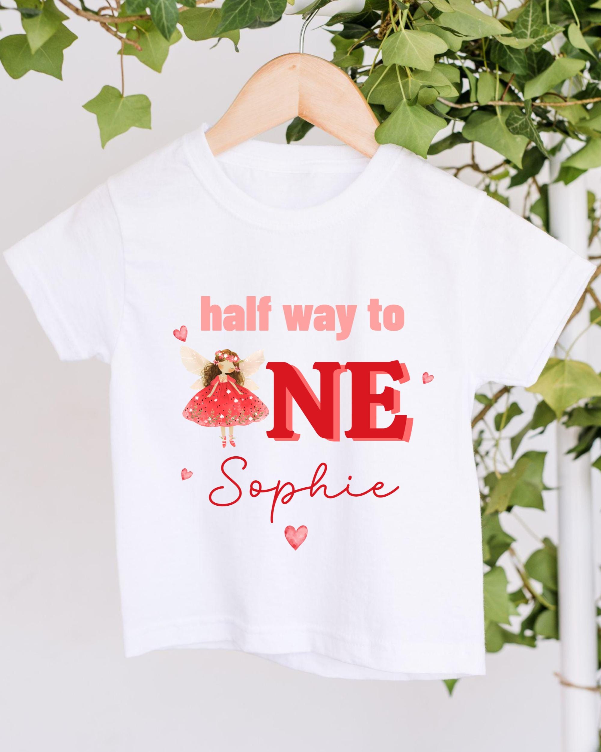 A white t-shirt with a graphic design featuring a fairy wearing a red dress and the text "half way to NE Sophie" printed on it.