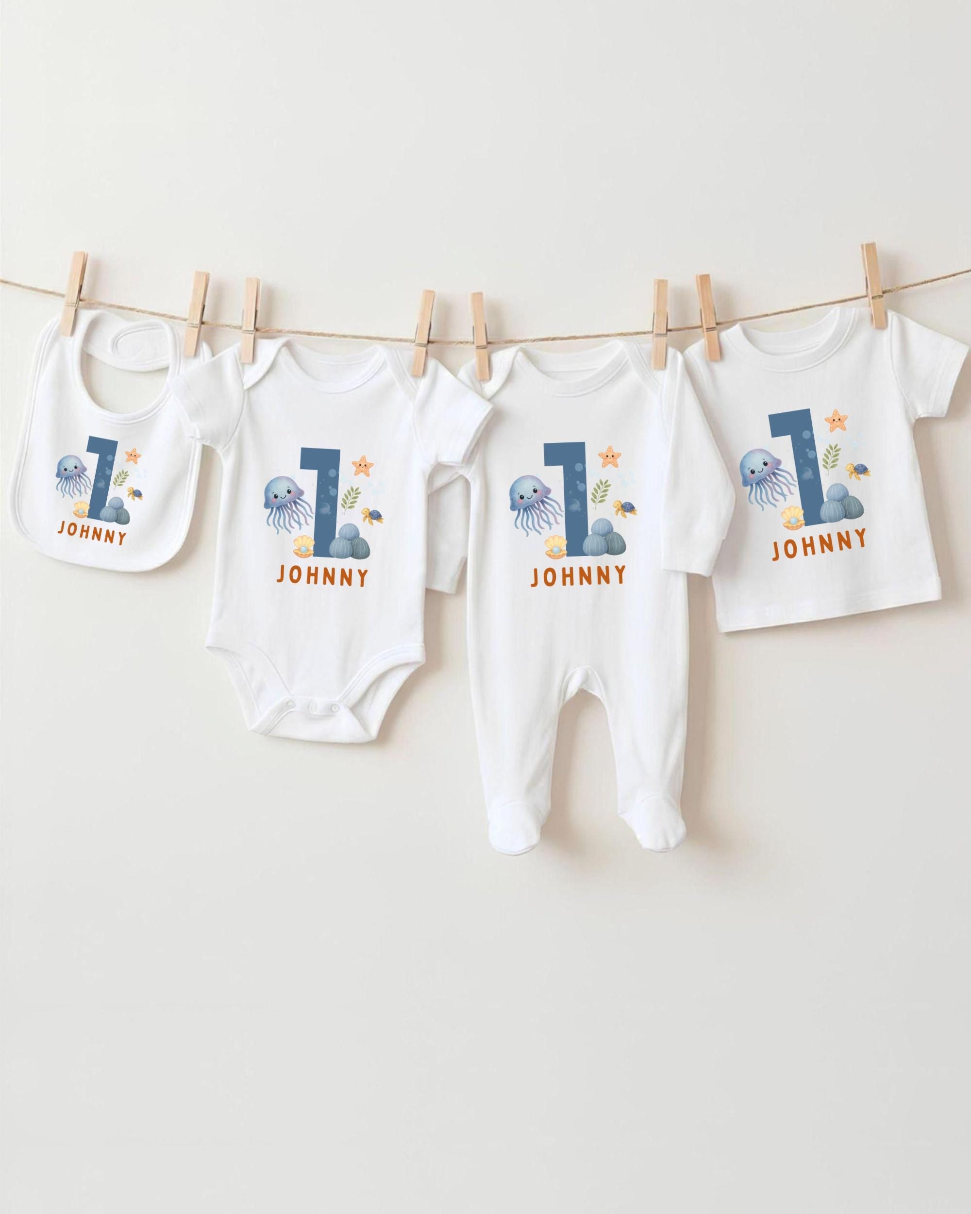 A collection of white baby clothes, including onesies and pajamas, with the number 1 printed on them. The clothes are hanging on a clothesline, with the number 1 prominently displayed on each item.