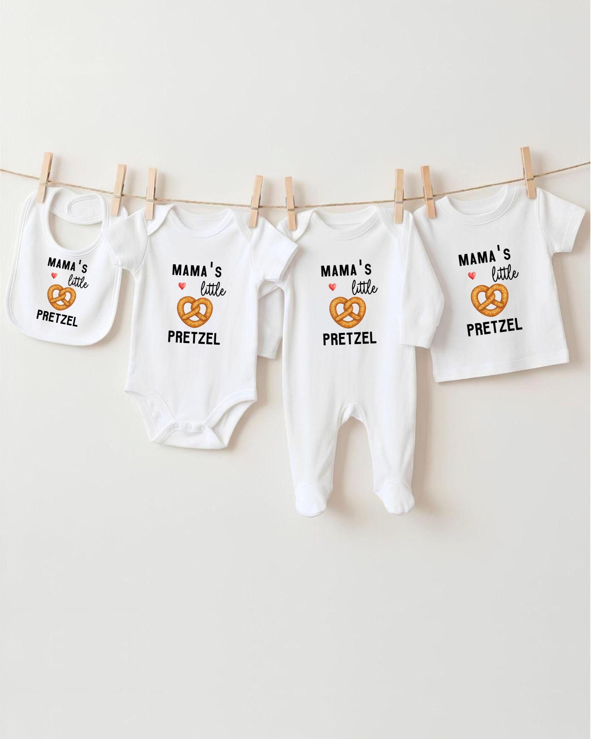 A row of four white baby clothes with the text "MAMA'S LITTLE PRETZEL" printed on them, along with a small pretzel icon.