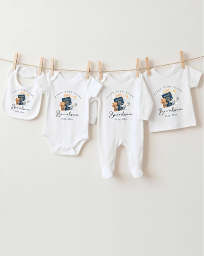 A row of four white baby clothes, including onesies and pajamas, hanging on a clothesline.