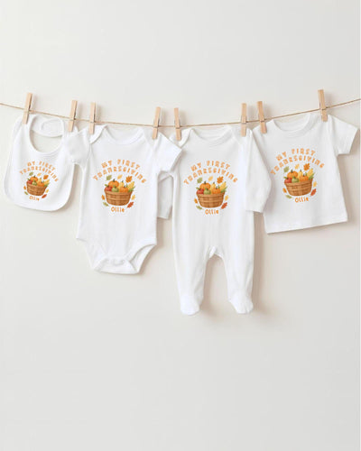 A collection of white baby clothes, including bodysuits and bibs, hanging on a clothesline.