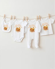 A collection of white baby clothes, including onesies and bibs, hanging on a clothesline.