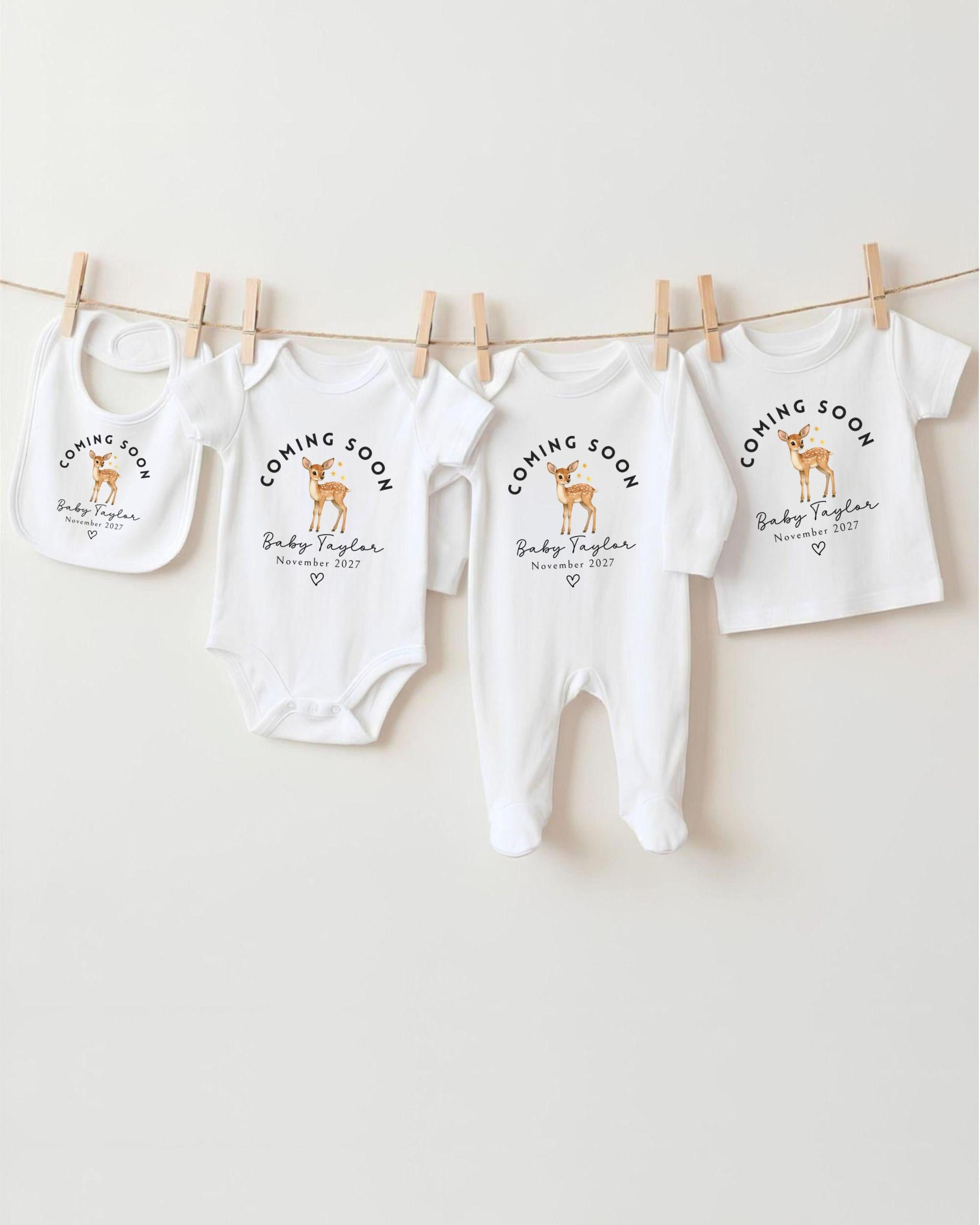 a collection of baby clothes hanging on a clothesline, with the clothes labeled as "Coming Soon" and featuring a deer design.
