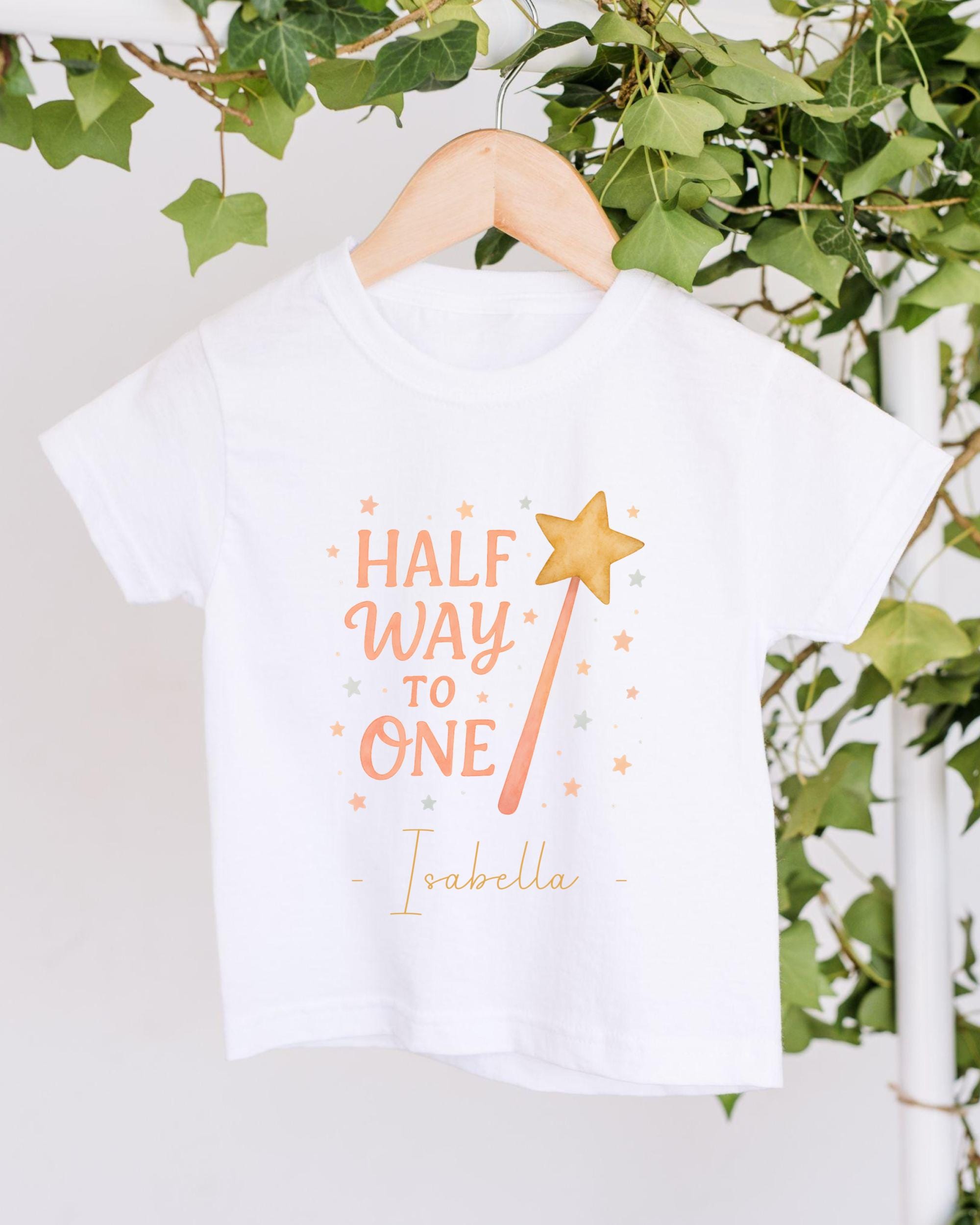 A white t-shirt with a graphic design and text printed on it, hanging on a wooden hanger.