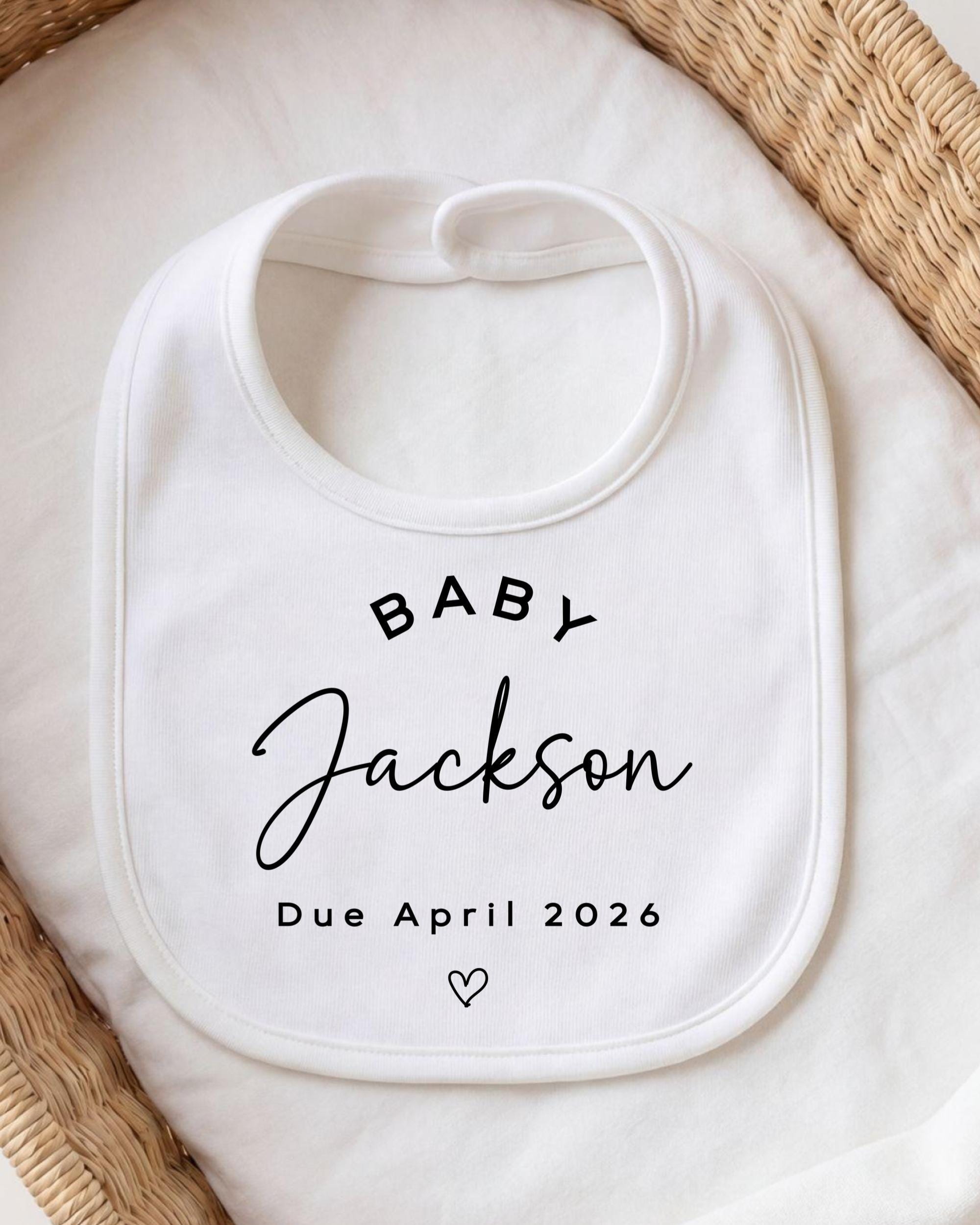 A white baby bib with the text "BABY JACKSON Due April 2026" printed on it.