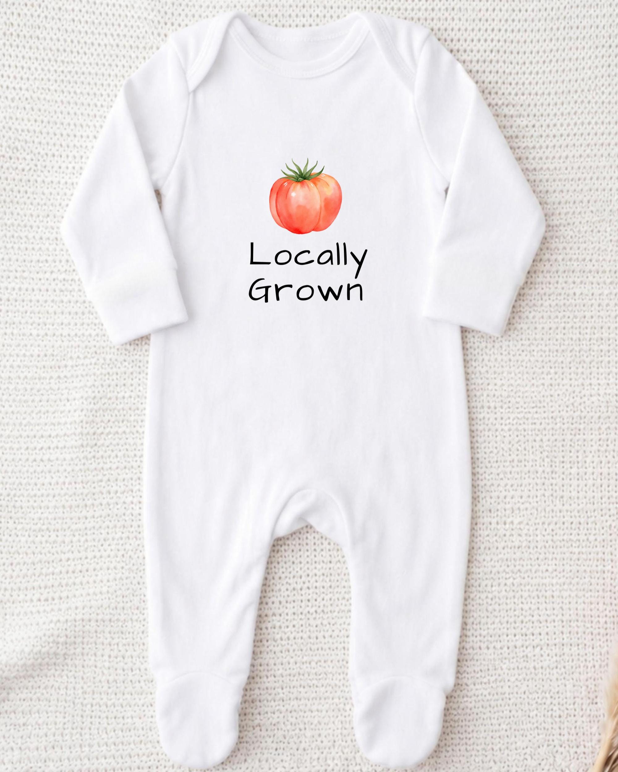 A white onesie with a printed tomato graphic and the text "Locally Grown" printed on it.