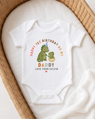 A white onesie with a dinosaur and a baby on it, placed on a white blanket.