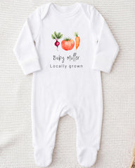 A white onesie with a graphic design of a carrot, tomato, and radish, along with the text "Baby Miller Locally grown".
