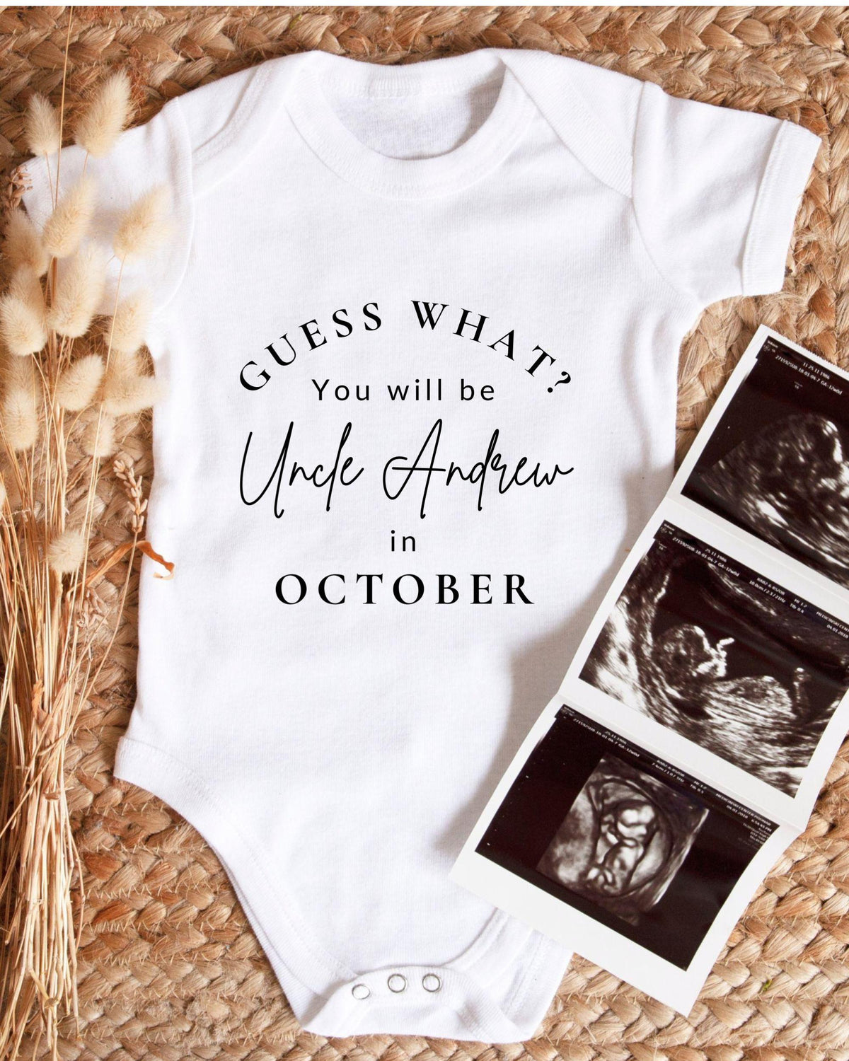 A white baby onesie with text that reads "Guess what? You will be Uncle Andrew in October" is displayed alongside a set of three black and white baby ultrasound images.