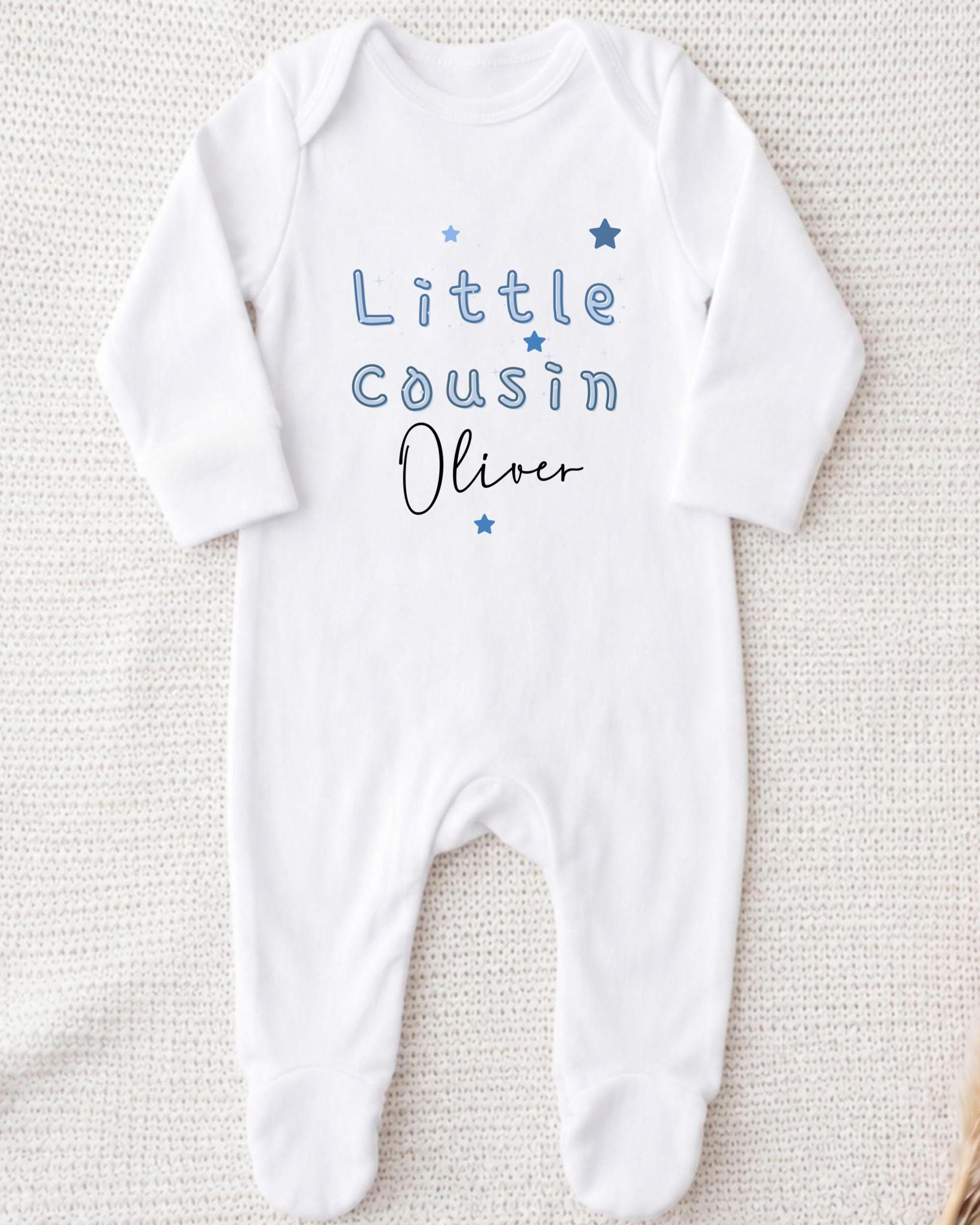 A white onesie with the text "Little Cousin Oliver" printed on it.