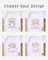 four different designs of white t-shirts, each featuring a hand-picked baby announcement. The designs include a rainbow, a sibling, a grandpa, and a nanny. The text on the t-shirts reads "Hand picked by Grandma in Heaven Baby Due Nov 2026" and "Hand picked by Brother in Heaven Baby Due Nov 2026".